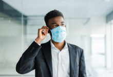 african business man wearing a mouth protection to prevent getting sick at work in office