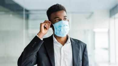 african business man wearing a mouth protection to prevent getting sick at work in office