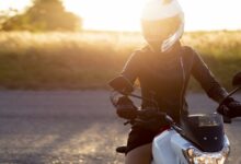 front view of woman with helmet riding her motorcycle in the sunset