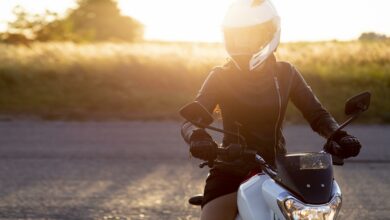 front view of woman with helmet riding her motorcycle in the sunset