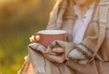 cup on sunset in hand young girl covered with a blanket